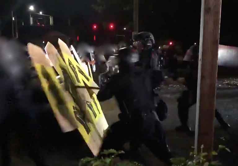 Фаланга протестующих со щитами обороняется от силовиков